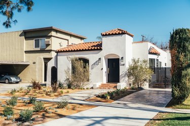 Front yard of a Spanish style white house with terra-cotta steps and roof tiles