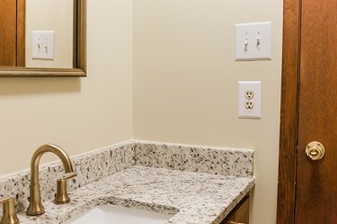 Beige walled bathroom with a light switch and double wall outlet
