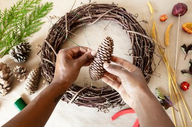 attaching a pine cone to a grapevine wreath base with wire