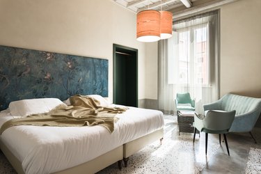 Bedroom with blue and green painted head board and sitting area with blue couches and chairs