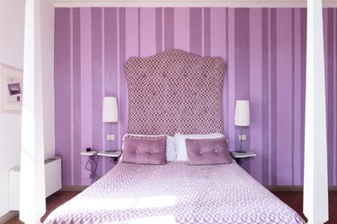 Monochormatic lavender badroom with fabric headboard and stroped wallpaper