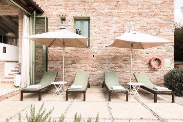 Green lounge chairs and umbrellas against brick wall