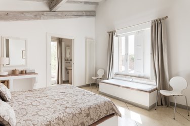 White bedroom with window bench and long curtains