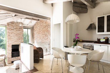 White mid-century modern kitchen with open sliding door to outdoor brick fireplace and sitting area