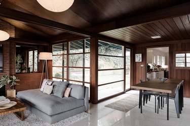 Midcentury paneled living and dining rooms with long rectangular windows.