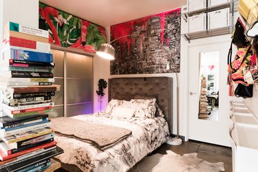 book storage in bedroom with grey bed and flamingo wall covering above closet doors