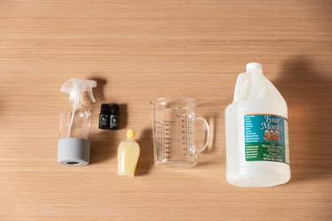 Spray bottle, eye dropper, measuring cup, and plastic jug on wooden countertop