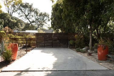concrete slab in the backyard, a horizontal wood fence, orange pots, large trees in the background