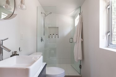 A minimalist all white bathroom and a shower with glass doors