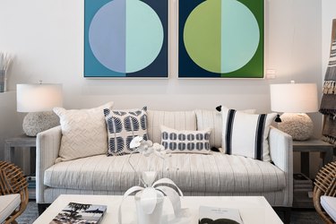 abstract art with blue and green hues hangs over a black and white couch