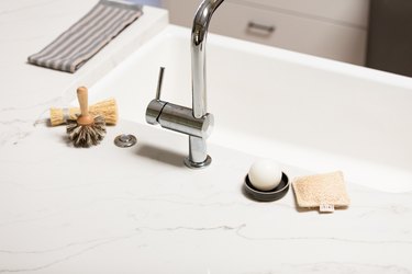 white countertop and chrome faucet and dish brush