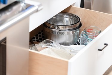 cooking dishes and bowls and measuring cups in open white drawer
