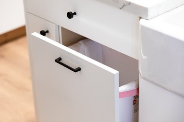 white kitchen cabinet with pull out trash can