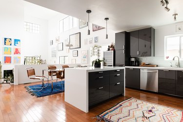 Gray cabinet kitchen and a dining room with wood furniture, and high gallery walls.