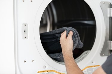 modern white dryer with hand reaching for laundry