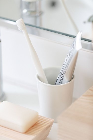 ceramic white cup and toothbrush and toothpaste
