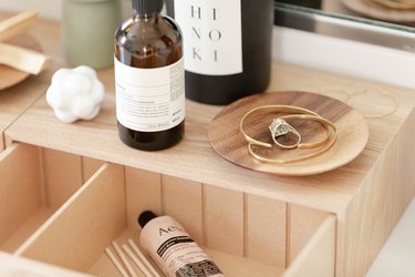 plywood bathroom storage with jewelry bowl and aesop skin care products
