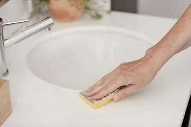 cleaning bathroom sink with sponge