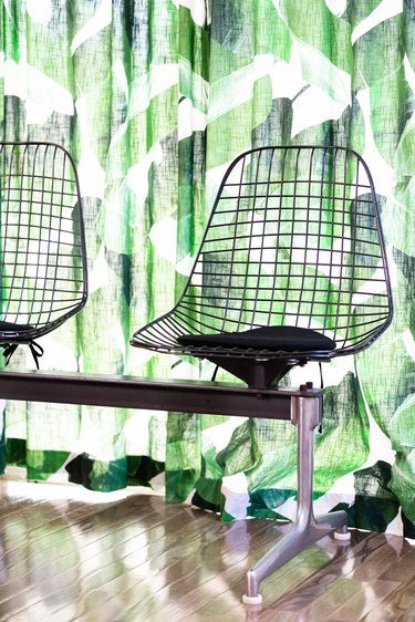 Eames wire chairs against leaf-patterned curtains