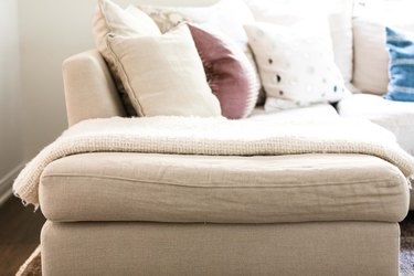 white blanket lying on cream couch with throw pillows