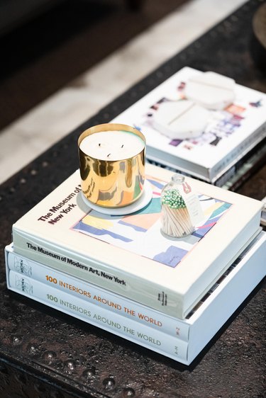 books stacked on table holding candle and matches