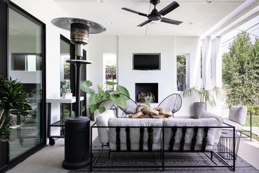 A porch with modern black accents, fireplace and a heating lamp