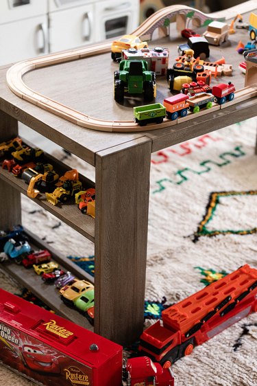 A wood table with children's toys and white rug with colorful details