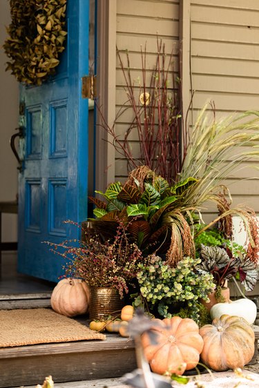 front door display with variegated plants and a mix of gourds