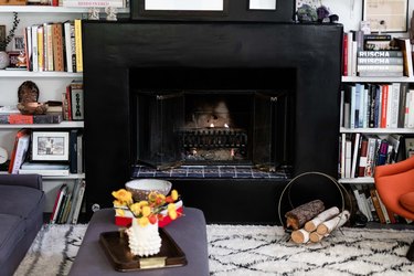 Black Room Ideas with Black mantle and fireplace with built in shelving, area rub, books, coffee table.