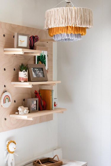 A fringe chandelier next to wood shelving with picture frames