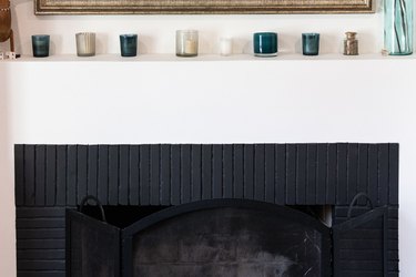 A black fireplace and white mantel with tea lights on top
