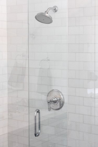 white subway tile, glass shower door, silver showerhead and handle
