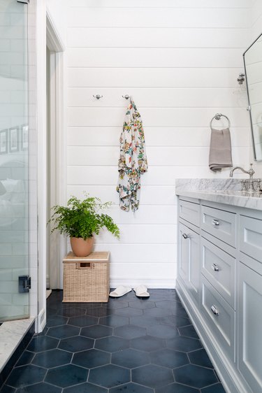 small minimalist bathroom with blue floor tiles and basket in a corner with a plant