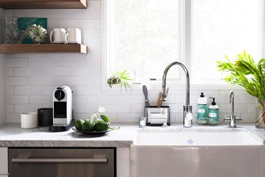 A white kitchen with open shelving, a coffee maker on the counter, and a stainless steel dishwasher