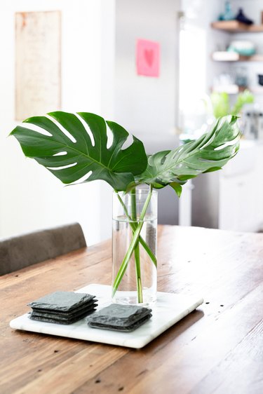 centerpiece tray with two large monstera leaves in simple clear vase