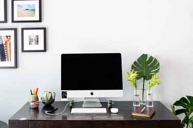 desk with apple desktop computer, plants, decor, and picture frames