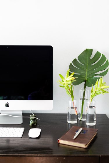 side of desk showing notebook, plants, keyboard, and monitor