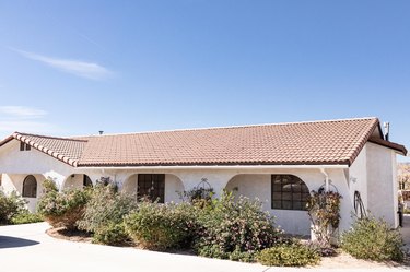 A white house with a brown roof under a blue sky.