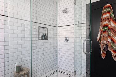 A glass shower with subway tile on the wall