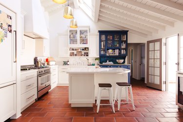 white kitchen with terra cotta tile and exposed wood beam ceiling