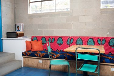 A colorfully cushioned wood bench and a wood table with turquoise chairs