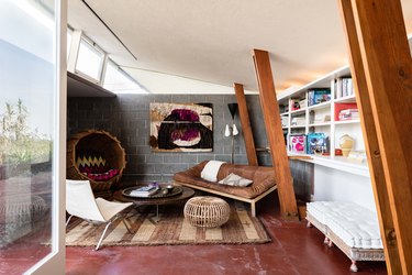 Mid-century living room with maroon floors, wood beams and gray walls