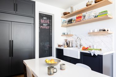 White-walled Kitchen with gray cabinets, white dining table and wood shelving