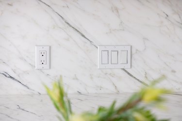 White lightswitch and outlet on marble wall
