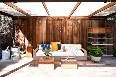 Outdoor storage and organization idea under wood pergola with sofa, plants, and shelving