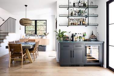 A dining room with wood floors and a gray cabinet Contemporary Bar with shelving