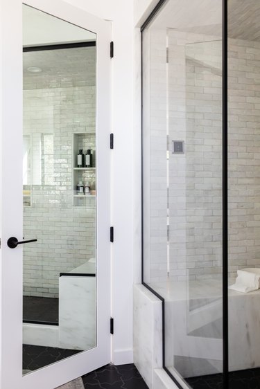 Bathroom door with a full-length mirror and a glass door shower