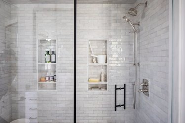 Glass door shower with gray wall tiles and shower niches.