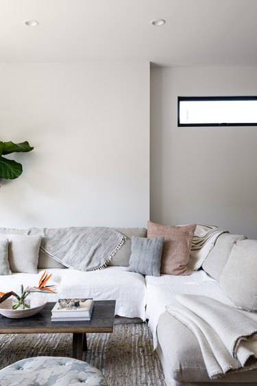 A living room sofa with pillows and blankets in a white-walled living room