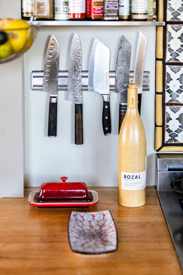 A wood countertop with dishware and a knife set mounted on a metal holder